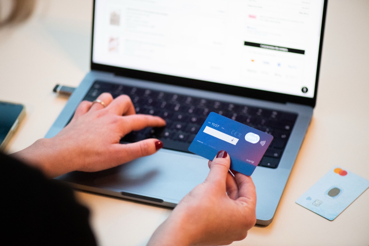 Persona pagando una compra online con tarjeta frente a una laptop