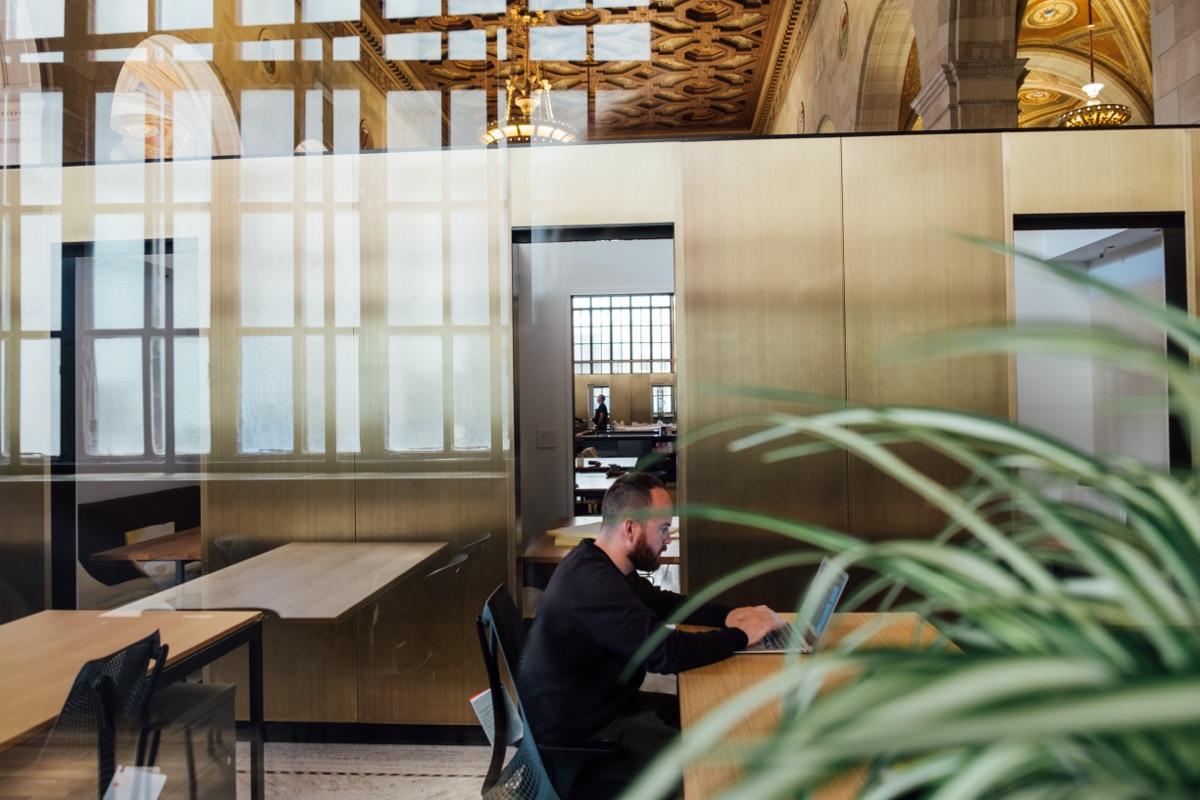 Equipo de trabajo discutiendo un proyecto alrededor de una mesa con laptops